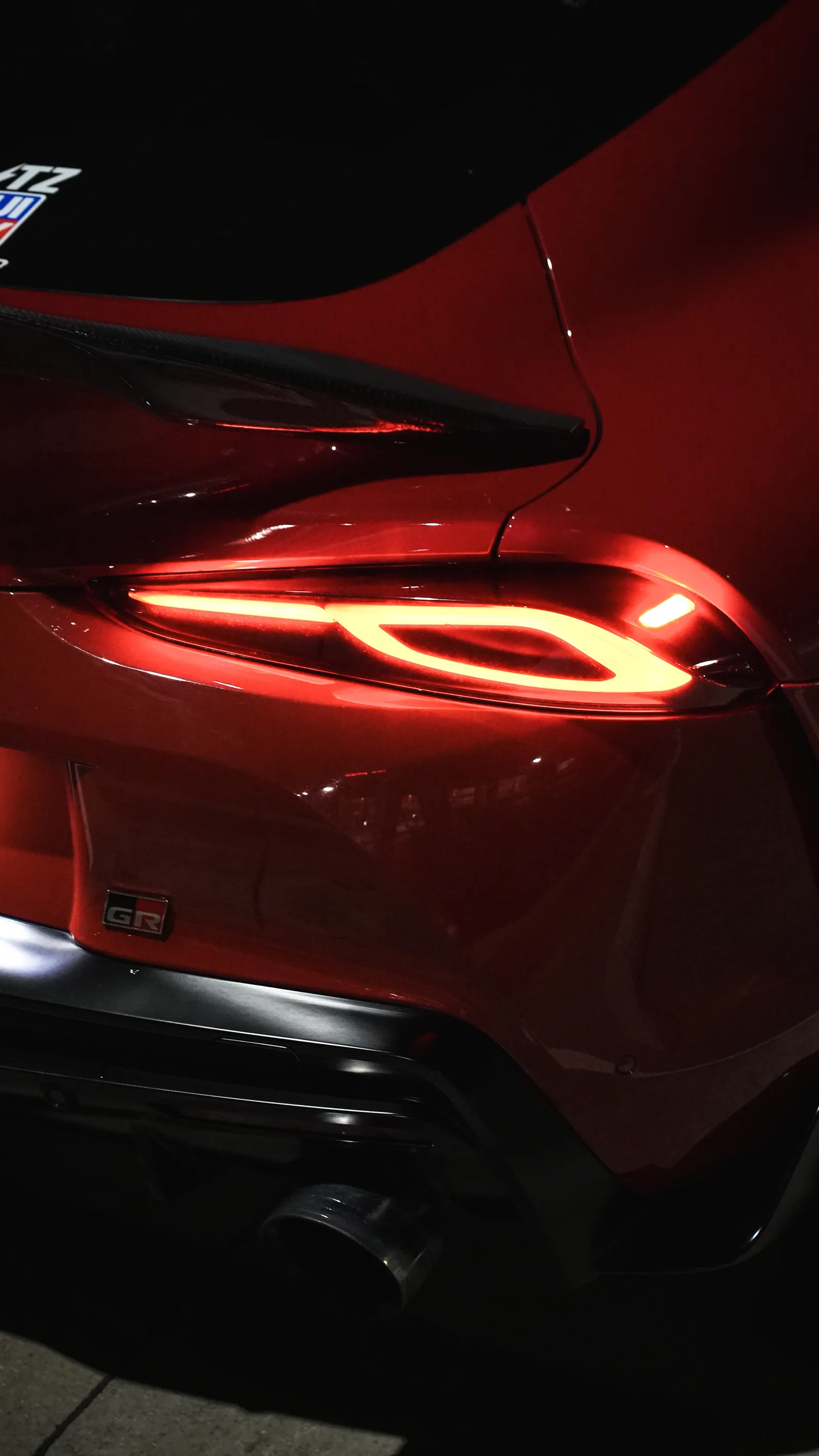 Polished red sports car rear quarter and taillight after paint enhancement